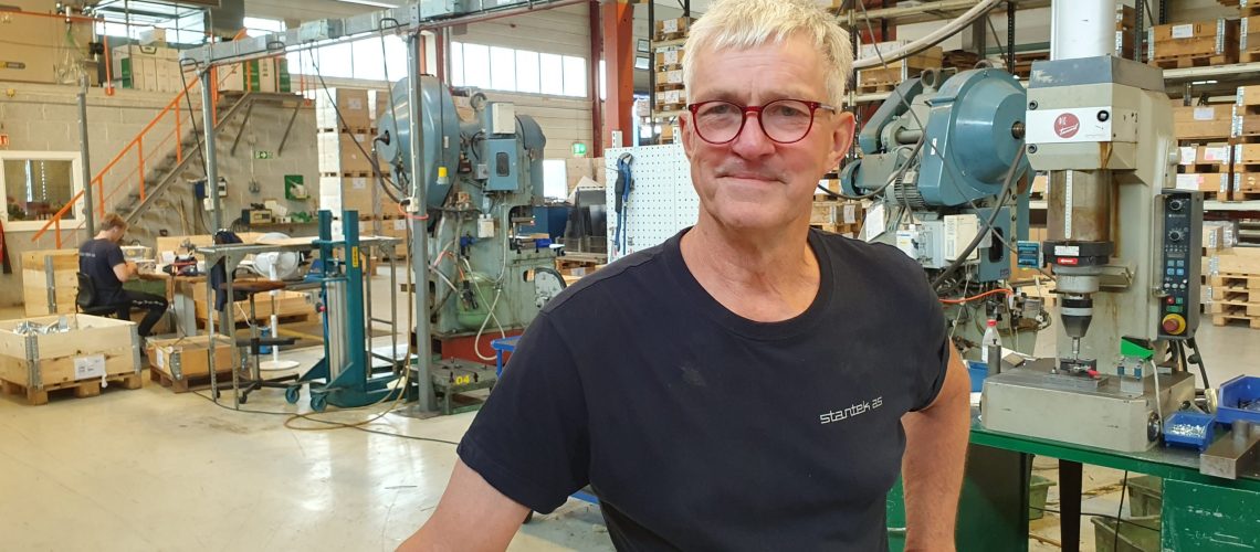 Bildet viser en smilende mann i en produksjonshall